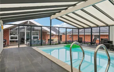 a swimming pool with a pergola next to a house at Nice Home In Blokhus With Sauna in Blokhus