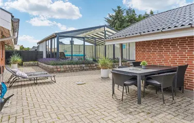 a patio with a table and chairs and a building at Nice Home In Blokhus With Sauna in Blokhus
