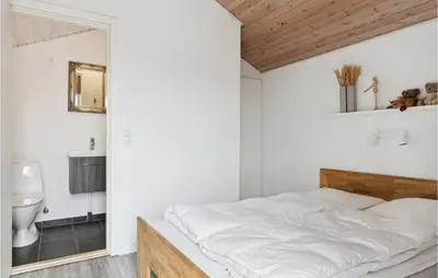 a white bedroom with a bed and a bathroom at Nice Home In Blokhus With Sauna in Blokhus