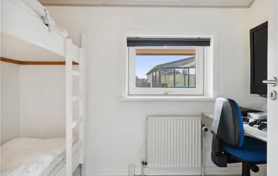 a bedroom with a bunk bed and a desk and a window at Nice Home In Blokhus With Sauna in Blokhus