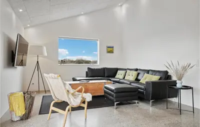 a living room with a black couch and a chair at Nice Home In Thisted With Sauna in Thisted