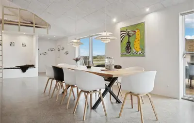 a dining room with a wooden table and white chairs at Nice Home In Thisted With Sauna in Thisted