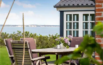 a table and chairs on a patio with a view of the water at Beach Front Home In Lemvig With Wifi in Lemvig