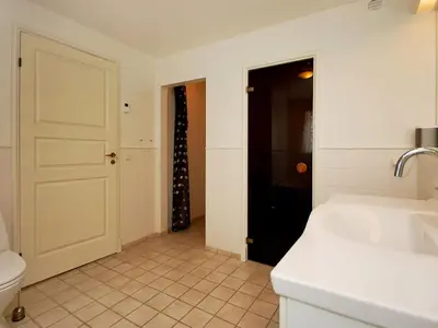 a bathroom with a sink and a toilet and a door at Holiday Home Alita - 1-2km from the sea by Interhome in Blokhus