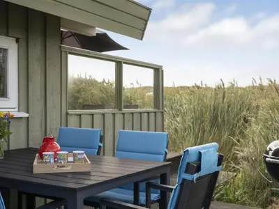 a wooden table and chairs on a porch with a window at Holiday Home Syni - 500m from the sea by Interhome in Pandrup