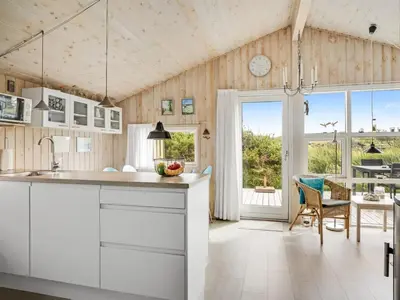 a kitchen with white cabinets and a dining room at Holiday Home Syni - 500m from the sea by Interhome in Pandrup
