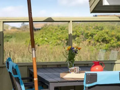 a table with a vase of flowers on a porch at Holiday Home Syni - 500m from the sea by Interhome in Pandrup