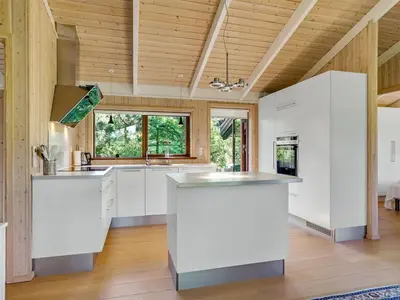 a kitchen with white cabinets and a wooden ceiling at Holiday Home Kali - 900m to the fjord by Interhome in Løgstør