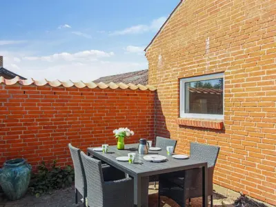 a table and chairs in front of a brick wall at Holiday Home Kiersten - 5km from the sea by Interhome in Saltum