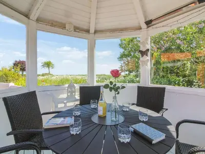 a table and chairs on a porch with a view of the ocean at Holiday Home Kiersten - 5km from the sea by Interhome in Saltum