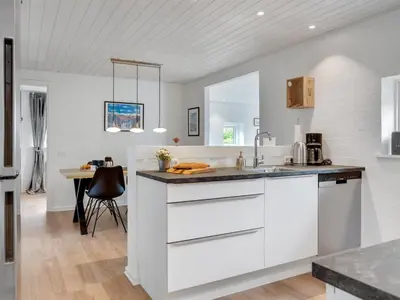 a white kitchen with a sink and a table at Holiday Home Kiersten - 5km from the sea by Interhome in Saltum