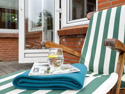a glass of wine sitting on a chair with a newspaper at Holiday Home Lisemarie - 800m from the sea by Interhome in Torsted