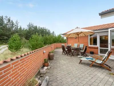 a patio with chairs and an umbrella on a brick wall at Holiday Home Lisemarie - 800m from the sea by Interhome in Torsted