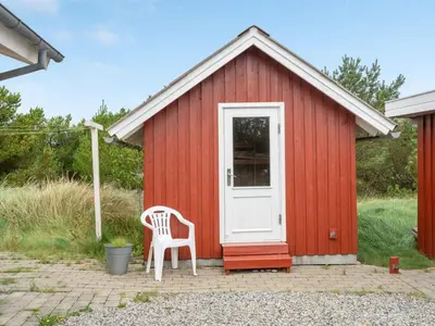 a red shed with a white door and a white chair at Holiday Home Lisemarie - 800m from the sea by Interhome in Torsted