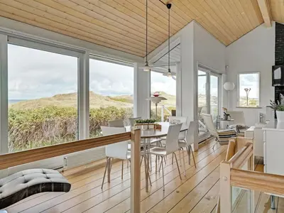 a dining room with a table and chairs and large windows at Holiday Home Ejvind - 100m from the sea by Interhome in Saltum