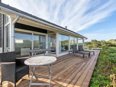 a wooden deck with a table and chairs on it at Holiday Home Ejvind - 100m from the sea by Interhome in Saltum