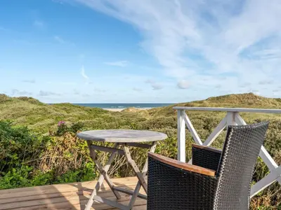 a table and chairs on a deck with the ocean at Holiday Home Ejvind - 100m from the sea by Interhome in Saltum