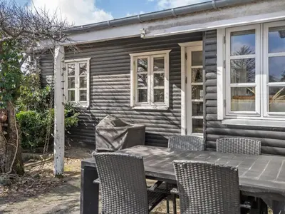 a table and chairs in front of a house at Holiday Home Sharanya - 500m from the sea by Interhome in Blokhus