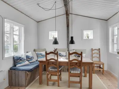 a dining room with a table and chairs and a couch at Holiday Home Sharanya - 500m from the sea by Interhome in Blokhus