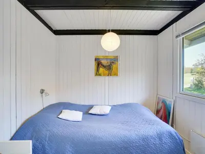 a bedroom with a blue bed with two pillows at Holiday Home Vasilij - 300m to the fjord by Interhome in Farsø