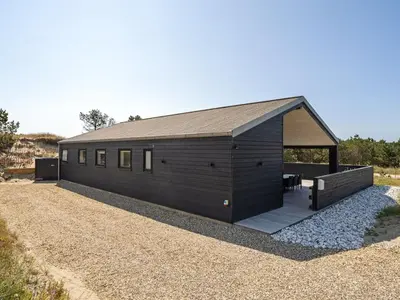 a black building with a roof on a gravel yard at Holiday Home Grimar - 600m from the sea by Interhome in Torsted