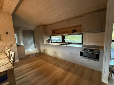 a kitchen with white cabinets and a wooden floor at Holiday Home Glenda - 3km from the sea by Interhome in Saltum
