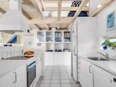 a kitchen with white cabinets and a wooden ceiling at Holiday Home Ritha - 350m from the sea by Interhome in Saltum