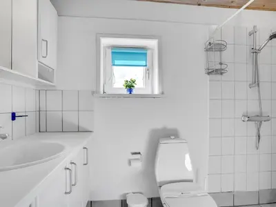 a white bathroom with a toilet and a window at Holiday Home Ritha - 350m from the sea by Interhome in Saltum