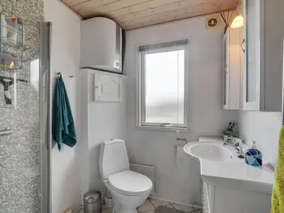a bathroom with a toilet and a sink and a window at Holiday Home Awer - 300m to the fjord by Interhome in Struer