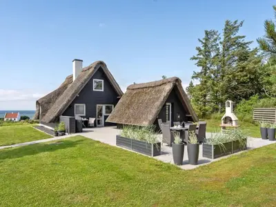 a house with a thatched roof and a patio at Holiday Home Aranja - 300m to the fjord by Interhome in Løgstør