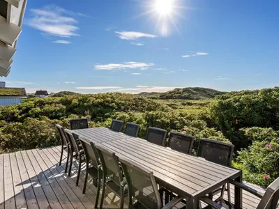 a wooden table and chairs on a deck with a view at Holiday Home Rauli - 50m from the sea by Interhome in Saltum