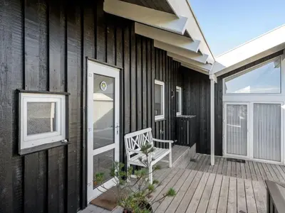 a wooden porch with a white bench on a house at Holiday Home Rauli - 50m from the sea by Interhome in Saltum