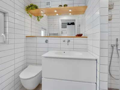 a white bathroom with a toilet and a sink at Holiday Home Rauli - 50m from the sea by Interhome in Saltum