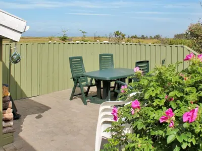 a patio with a table and chairs and flowers at Holiday Home Annick - 300m from the sea by Interhome in Fjerritslev