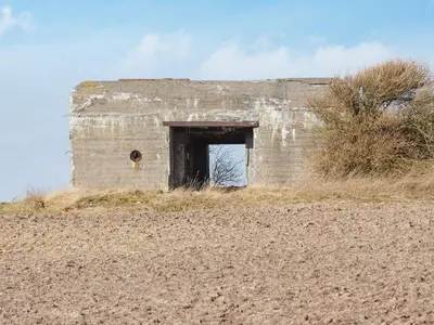 a brick building with a door in a field at 12 person holiday home in Lemvig-By Traum in Lemvig