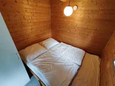 a small room with a bed in a wooden cabin at Tranum Klit Camping og Hytteudlejning in Brovst