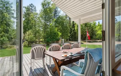 a patio with a wooden table and chairs on a deck at 3 Bedroom Awesome Home In Højslev in Højslev