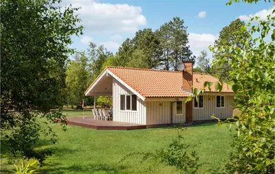 a white cottage with a deck in a yard at 3 Bedroom Awesome Home In Højslev in Højslev