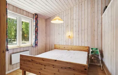 a bedroom with a wooden bed and a window at 3 Bedroom Awesome Home In Højslev in Højslev
