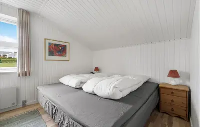 a bedroom with a bed with white sheets and a window at 2 Bedroom Cozy Home In Lemvig in Lemvig